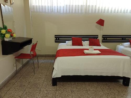 a bedroom with a bed with a red blanket and a desk at Hotel Resident Piura in Piura