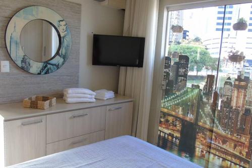 a bedroom with a television and a window with a view at Apartamento aconchegante e completo no centro de Ponta Grossa - Paraná in Ponta Grossa