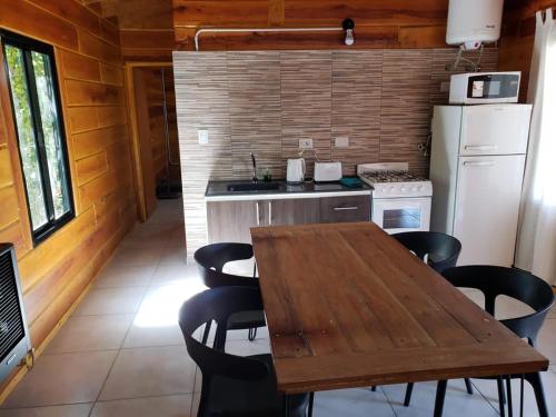 a kitchen with a wooden table and black chairs at Cabañas Puesta del Sol in Villa Yacanto