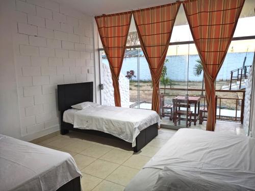 a bedroom with two beds and a balcony at Zorritos Backpakers in Tumbes