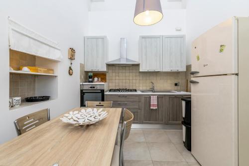 a kitchen with a wooden table and a white refrigerator at Le Bianche Suites Ostuni in Ostuni
