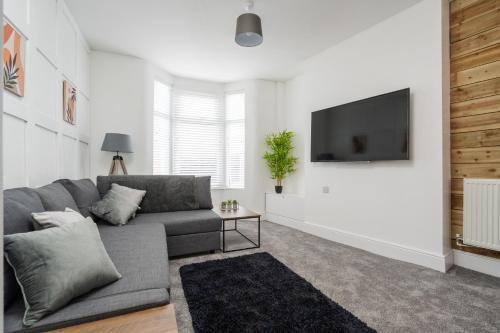 a living room with a couch and a flat screen tv at Harrow Lodge - Anfield Apartments in Liverpool