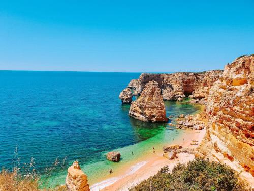 a beach with rocks and people in the water at Regenbogen Properties - Salgados Vila das Lagoas in Albufeira
