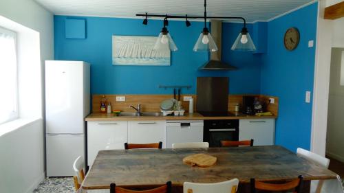 une cuisine avec une table en bois et un mur bleu dans l'établissement La cousinade No, à Noirmoutier-en-l'lle