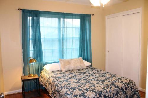 a bedroom with a bed with blue curtains and a window at Birchwood Place in Little Rock