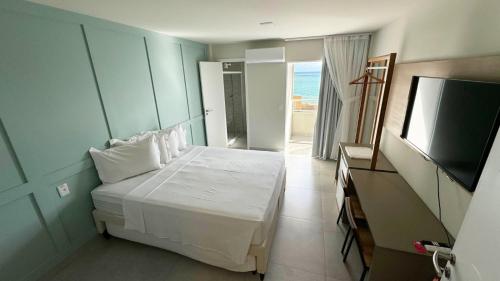 a bedroom with a bed and a flat screen tv at Liiv Mar - Natal Ponta Negra in Natal