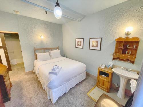 1 dormitorio con cama blanca y lavamanos en Alaskan Hotel and Bar en Juneau