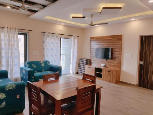 sala de estar con mesa, sillas y TV en Luxury 2BHK Apartment Near Candolim en Nerul