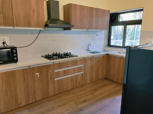 a kitchen with wooden cabinets and a black stove top oven at Luxury 2BHK Apartment Near Candolim in Nerul