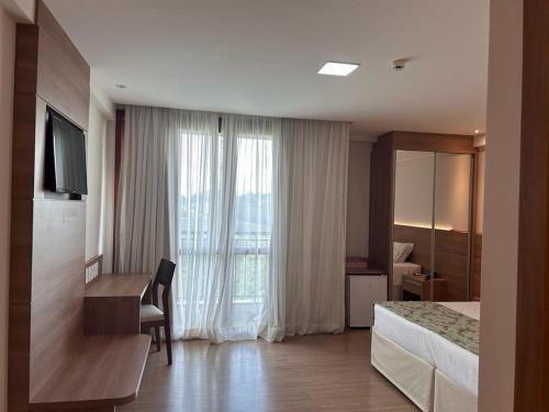 Cette chambre comprend un lit, un bureau et une fenêtre. dans l'établissement Vista Azul Hotel, à Domingos Martins