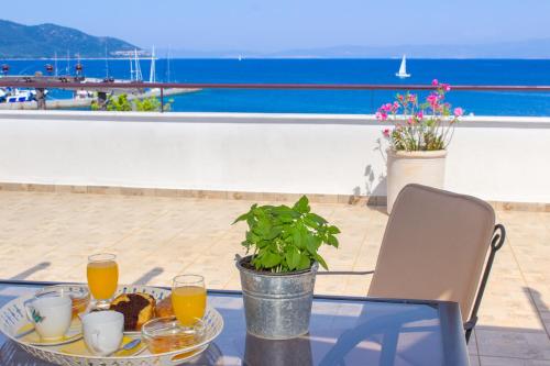 a glass table with a plate of food and orange juice at Hotel Galini in Limenas