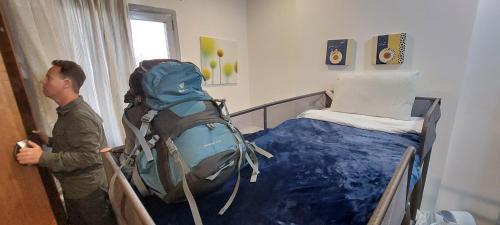 a man standing next to a bed with a backpack at Aladdin hostel in Kuwait