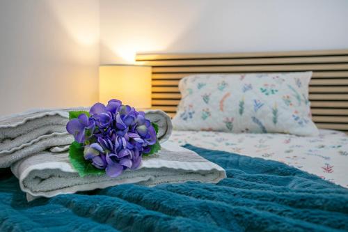 um ramo de flores roxas em cima de uma cama em Casa da Belinha em Ponta Delgada