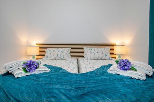 uma cama com lençóis azuis e flores roxas em Casa da Belinha em Ponta Delgada