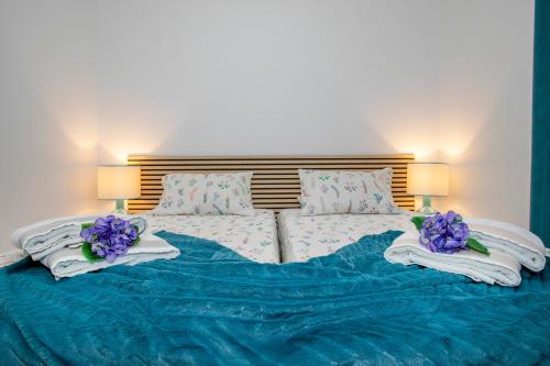 een bed met blauwe lakens en paarse bloemen erop bij Casa da Belinha in Ponta Delgada