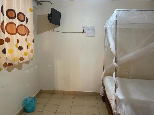 a small room with a bed and a curtain at Lexingtone Square in Igoji