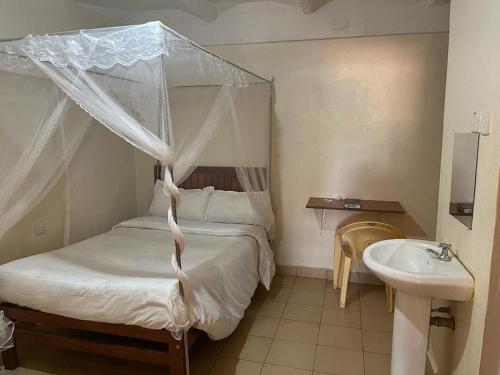 a bedroom with a canopy bed and a sink at Lexingtone Square in Igoji