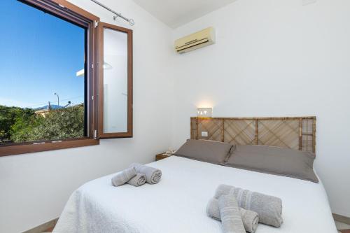 Un dormitorio con una cama blanca con toallas. en Scirocco a pochi passi dal mare en Santa Maria Navarrese
