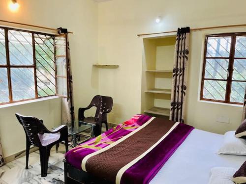 a bedroom with a bed and two chairs and two windows at Naivedyam villa in Mount Ābu