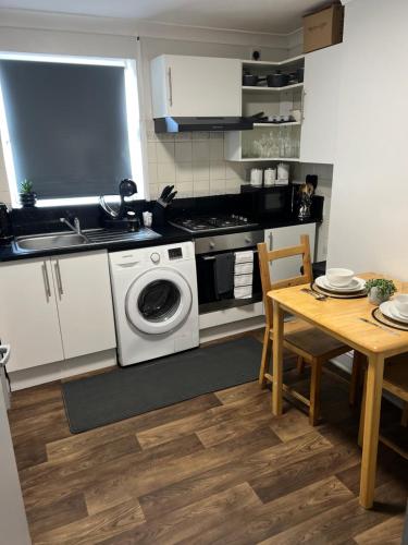 a kitchen with a washing machine and a table at Dalston 1 bedroom flat in London