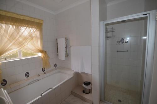 a white bathroom with a tub and a shower at Attaché Guest Lodge & Health Spa in Midrand