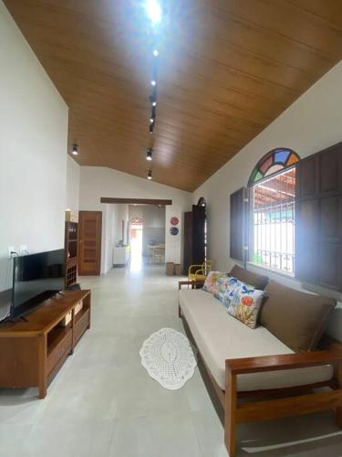 uma sala de estar com um sofá e uma televisão em CASA Praia Cacha Pregos em Vera Cruz de Itaparica