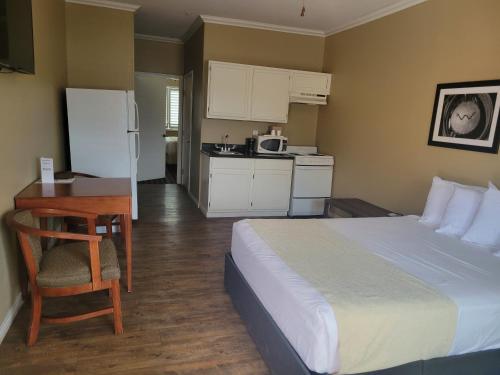 a bedroom with a bed and a desk and a kitchen at Cotulla Whitten Inn in Cotulla