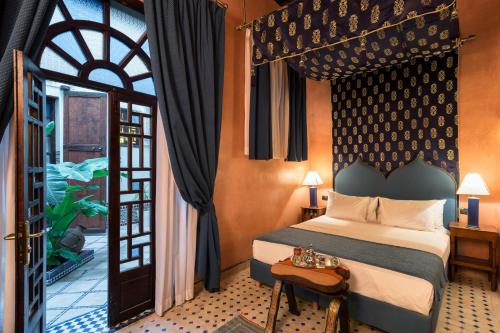 a bedroom with a bed and a door to a balcony at Algilà Fes Riad Medina Charme Hotel in Fez