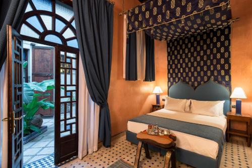 una camera con letto e porta di accesso a un balcone di Algilà Fes Riad Medina Charme Hotel a Fes