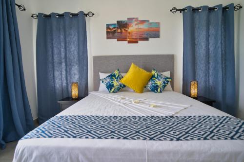 a bedroom with a bed with blue curtains at Sunset Haven Villa in Beau Vallon