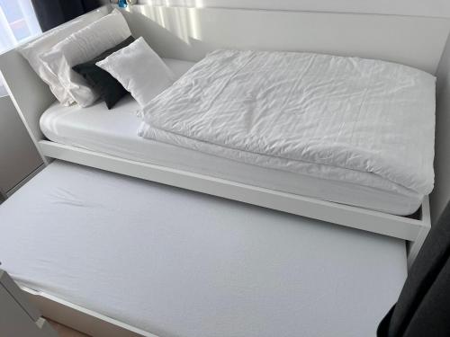 Una cama con sábanas blancas y almohadas. en Unterkunft am Steinhuder Meer, en Wunstorf