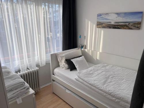 Un pequeño dormitorio con una cama blanca y una ventana en Unterkunft am Steinhuder Meer, en Wunstorf