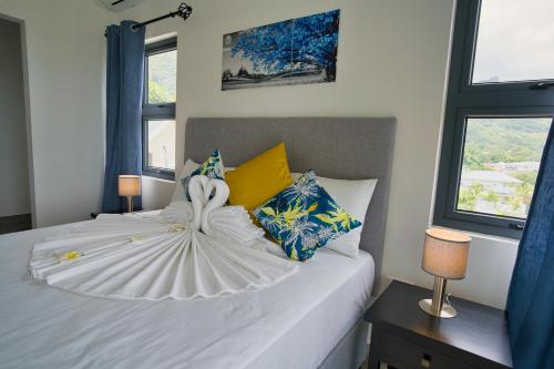 a bedroom with a white bed with two windows at Sunset Haven Villa in Beau Vallon
