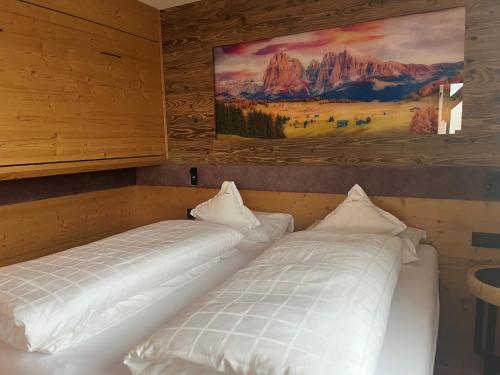 twee bedden in een kamer met een schilderij aan de muur bij A Sosta in Selva di Val Gardena