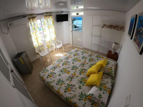 1 dormitorio con 1 cama grande con almohadas amarillas en Native Lodge Brisas del Sur, en Providencia
