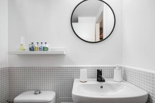 uma casa de banho branca com um lavatório e um espelho em the container house em Ra‘ananna