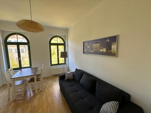 a living room with a black couch and a table at Chez Amis Arena in Leipzig