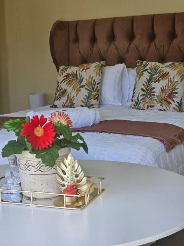 a bed with a table with flowers on it at MorningMist Boutique Sun in Centurion
