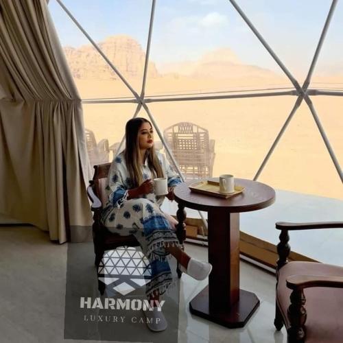a woman sitting at a table with a cup of coffee at Harmony Luxury Camp in Wadi Rum