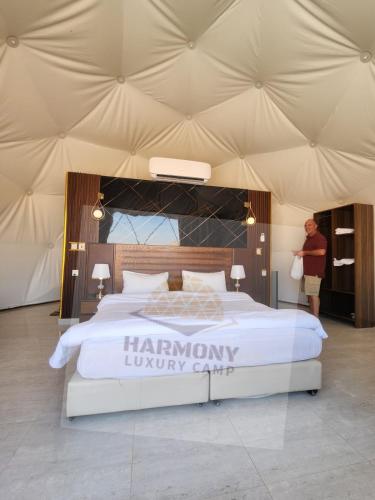 a man standing next to a large bed in a tent at Harmony Luxury Camp in Wadi Rum