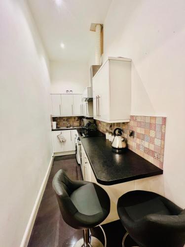 a kitchen with white cabinets and black counter tops at STYLISH 1Bhk HEART OF THE CITY in Edinburgh