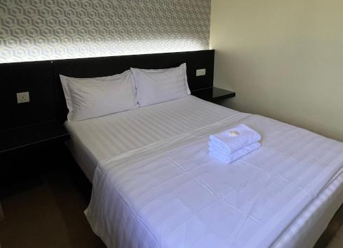 a white bed with two towels on top of it at Pekan Auto City Budget Hotel in Pekan
