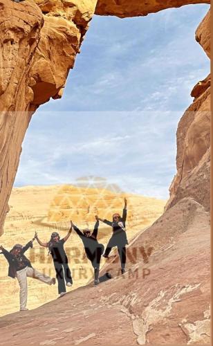a group of people jumping through a rock formation at Harmony Luxury Camp in Wadi Rum