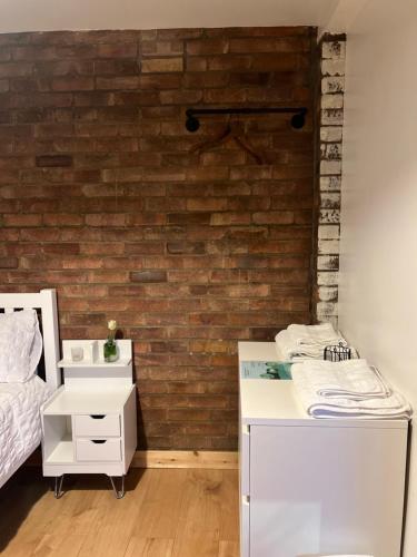 una camera da letto con mobili bianchi e un muro di mattoni di Hidden Havens a Norwich