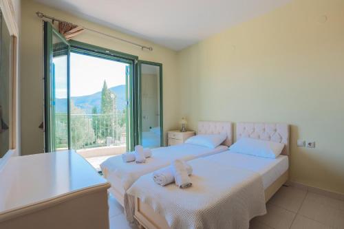two beds in a room with a large window at Scorpios Villa in Kefallonia