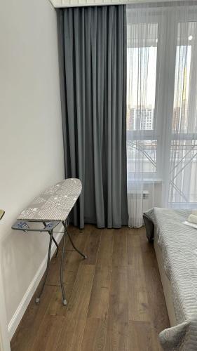 a bedroom with a bed and a table and a window at Люкс Апартаменты в центре левого берега Астаны in Taldykolʼ
