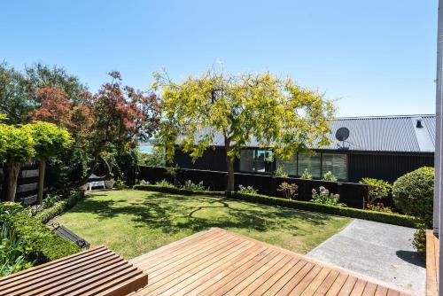a backyard with a wooden deck and a yard with trees at Retro Living - Lush Garden in Christchurch