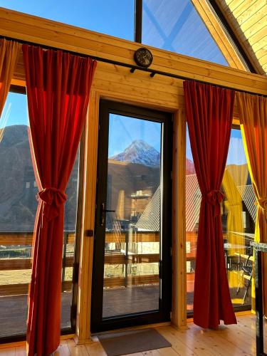 a room with red curtains and a view of a mountain at Kazbegi Inn Cottages in Stepantsminda