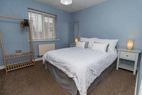 a blue bedroom with a bed and a window at DWELLCOME HOME Ltd Spacious 3 Double Bedroom Boldon Townhouse - see our site for assurance in Boldon