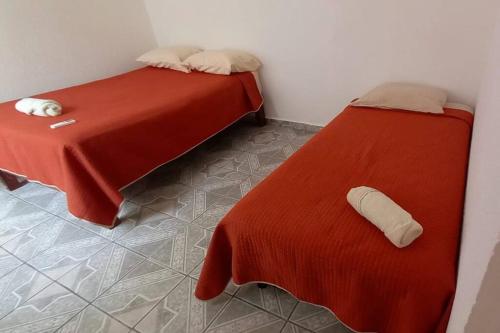 a bedroom with two beds with red sheets and a pillow at Casa Andrea. Crucecita Huatulco. in Santa Cruz Huatulco